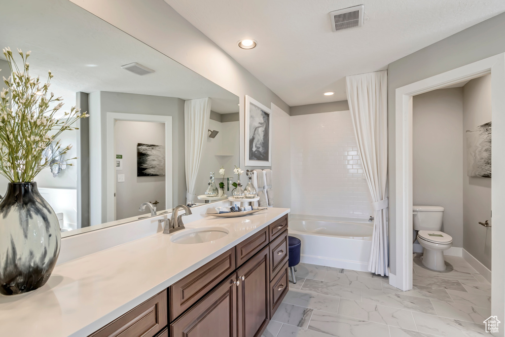 Bathroom featuring vanity, a bathtub, and toilet