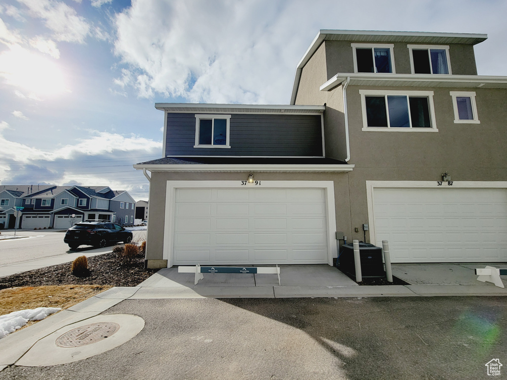 View of front of property featuring a garage and cooling unit