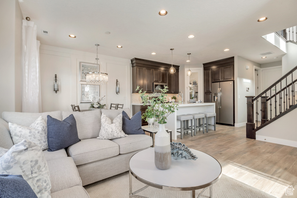 Living room featuring sink, light hardwood / wood-style flooring, and a notable chandelier