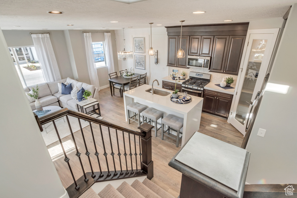 Kitchen with appliances with stainless steel finishes, decorative light fixtures, sink, and light wood-type flooring