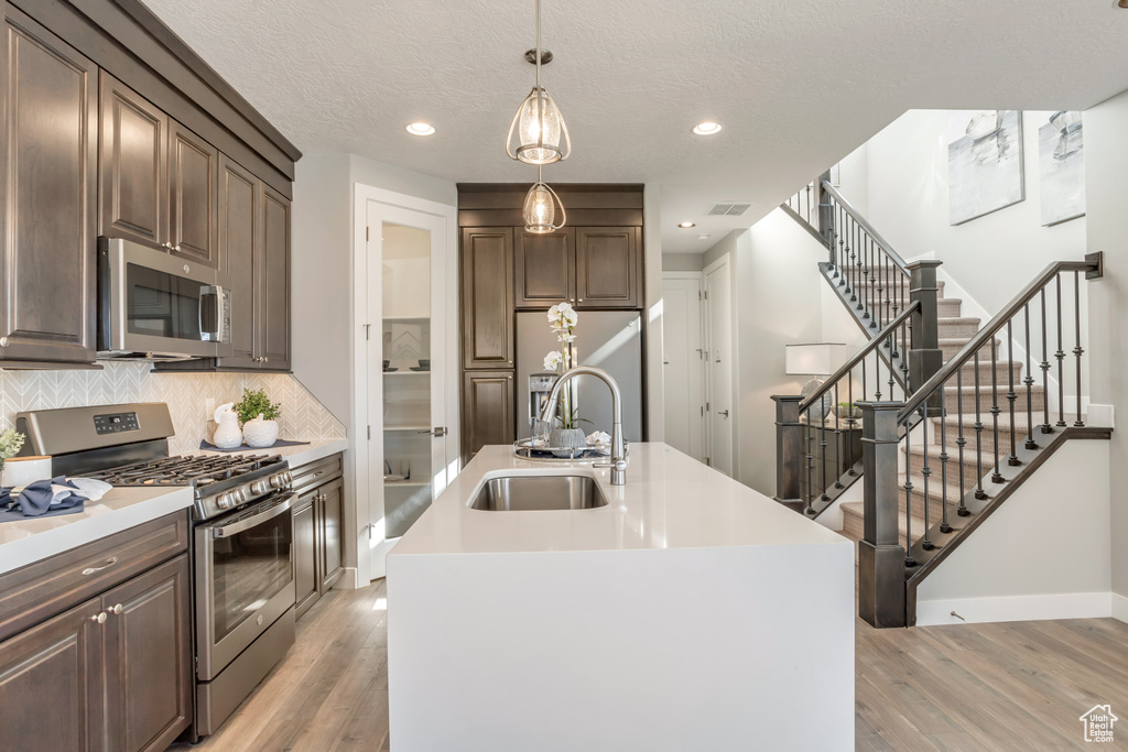 Kitchen featuring an island with sink, stainless steel appliances, sink, and backsplash
