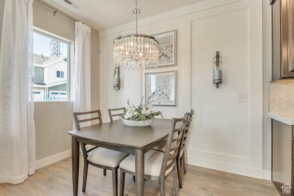 Dining room featuring a healthy amount of sunlight, a chandelier, and light hardwood / wood-style flooring