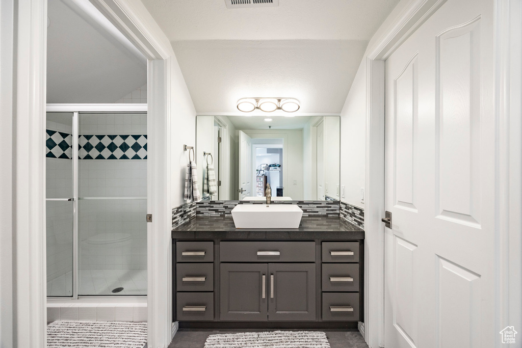 Bathroom featuring a shower stall, vanity, and tasteful backsplash