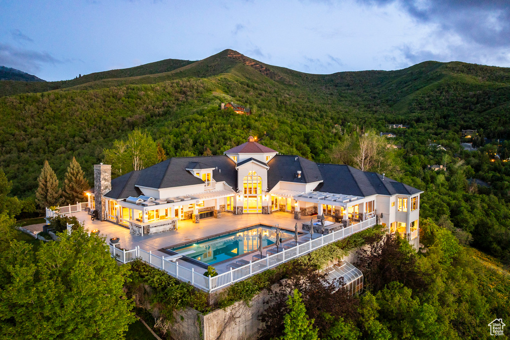 View of subject property with a forest, a mountainous background, and a pool