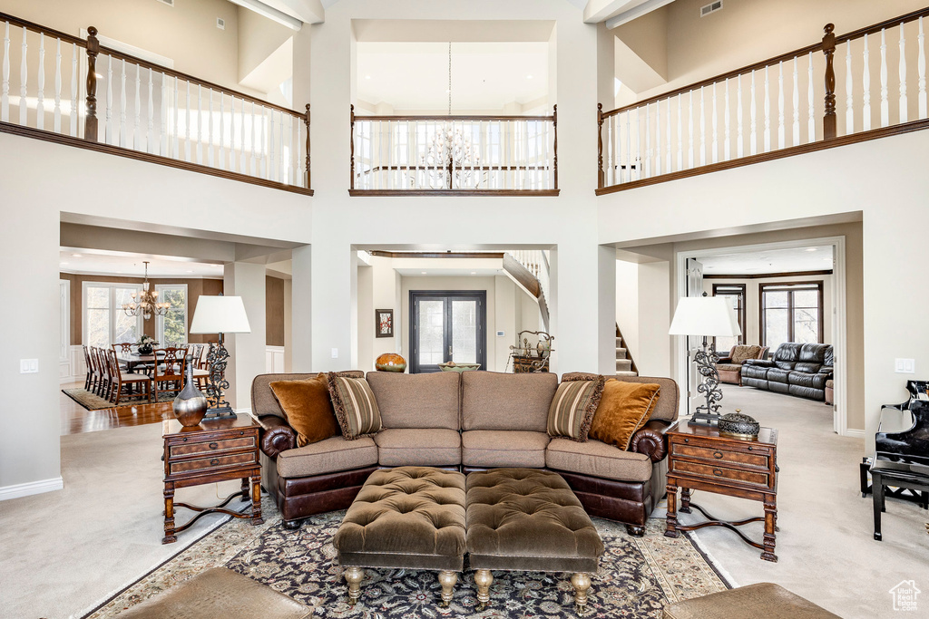 Living room featuring a chandelier, carpet, stairway, plenty of natural light, and a high ceiling