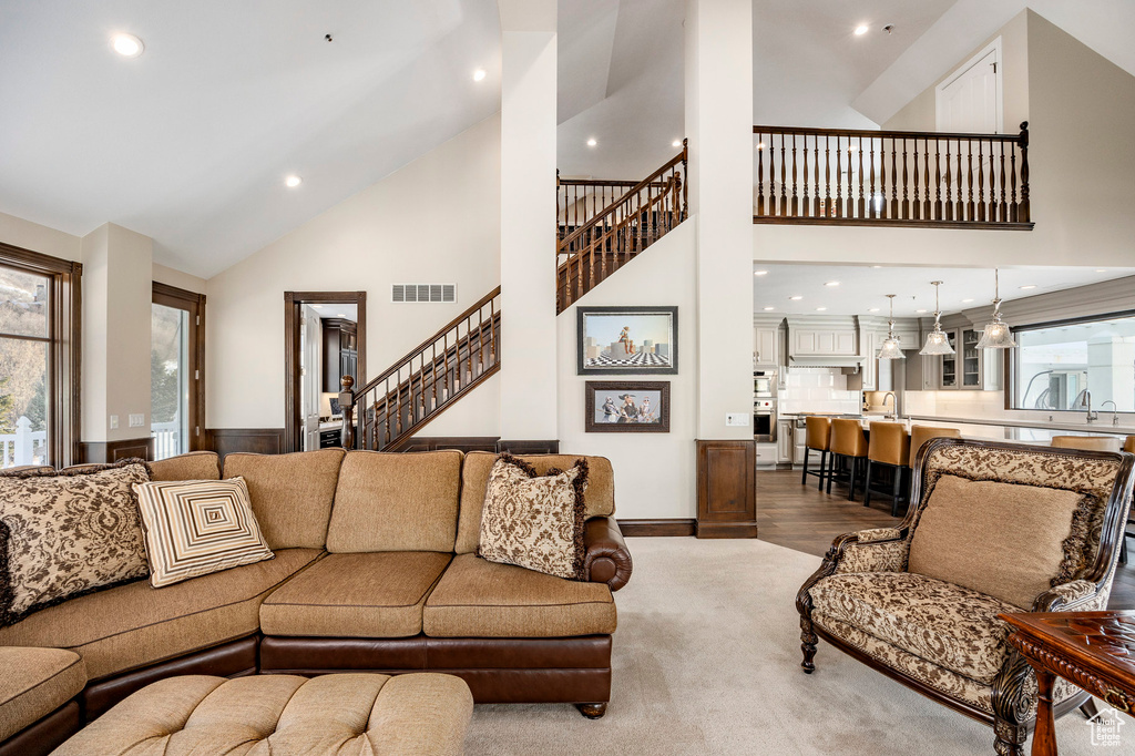 Living room featuring high vaulted ceiling, stairs, and recessed lighting