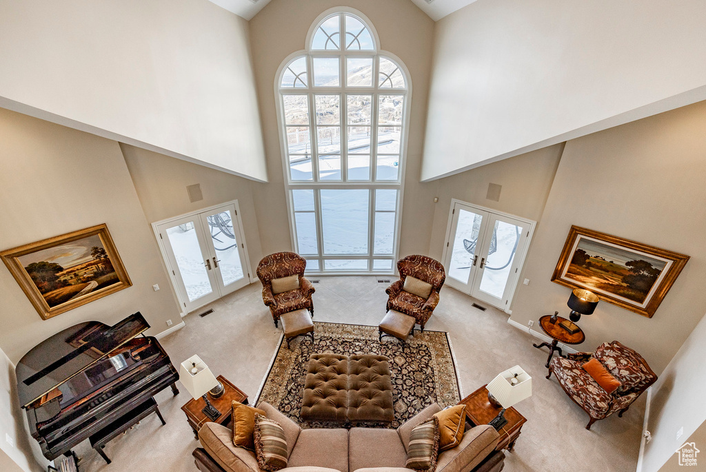 Living area featuring french doors, high vaulted ceiling, healthy amount of natural light, and carpet floors