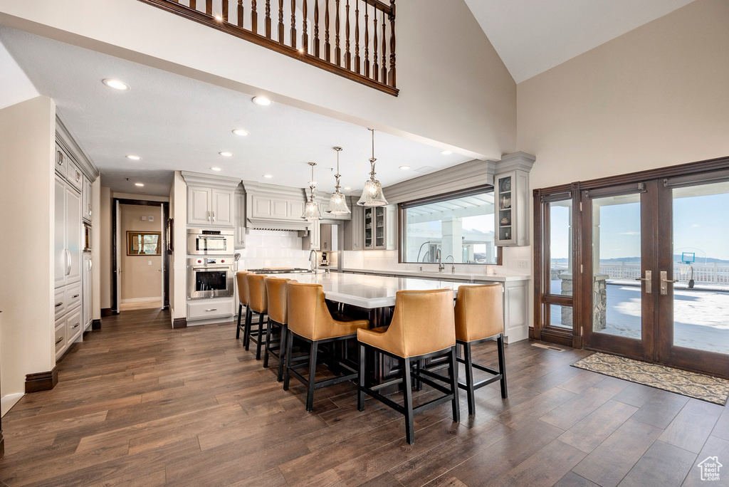 Dining area with dark wood finished floors, high vaulted ceiling, french doors, and recessed lighting