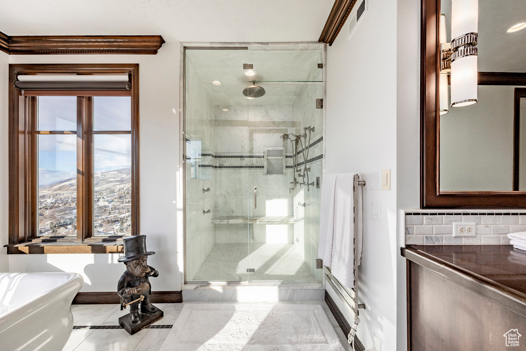 Full bathroom featuring baseboards, a shower stall, a soaking tub, backsplash, and marble finish flooring