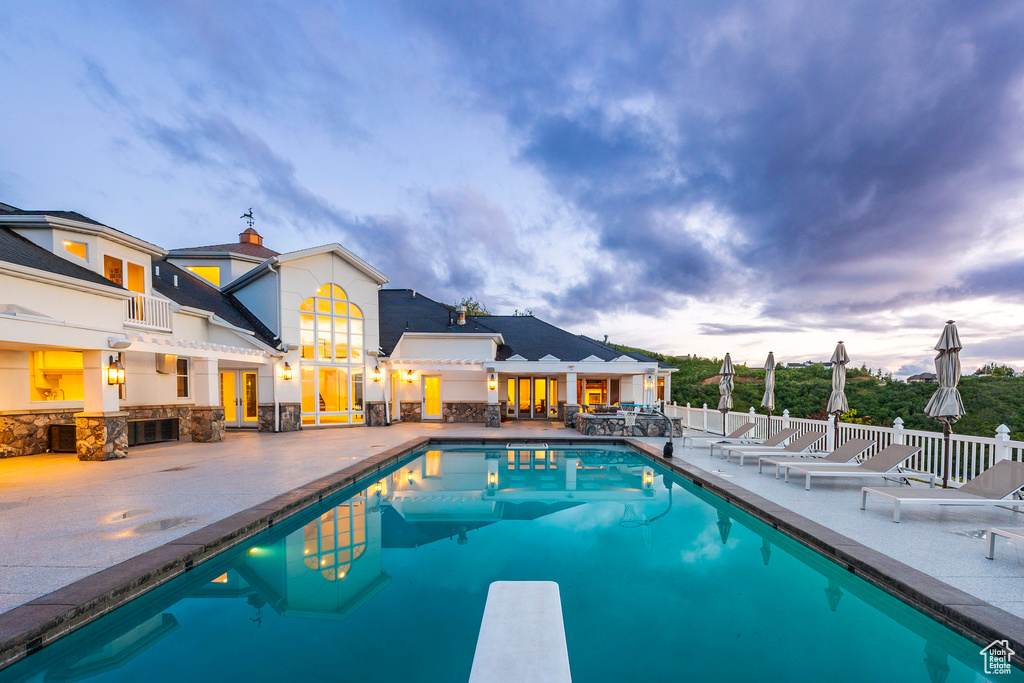 View of pool with a patio area and a diving board
