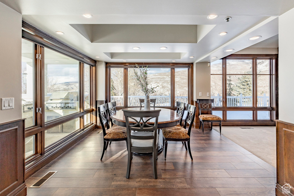 Dining room with dark wood-type flooring, expansive windows, recessed lighting, and a tray ceiling