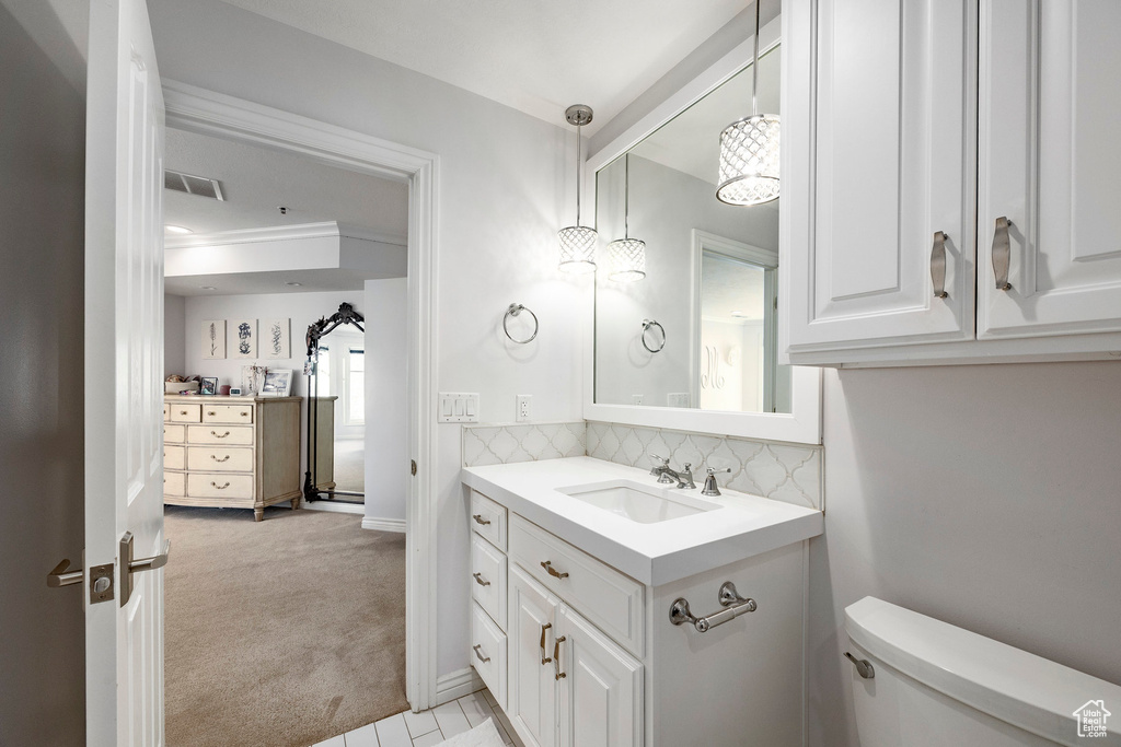 Bathroom featuring vanity, toilet, and decorative backsplash