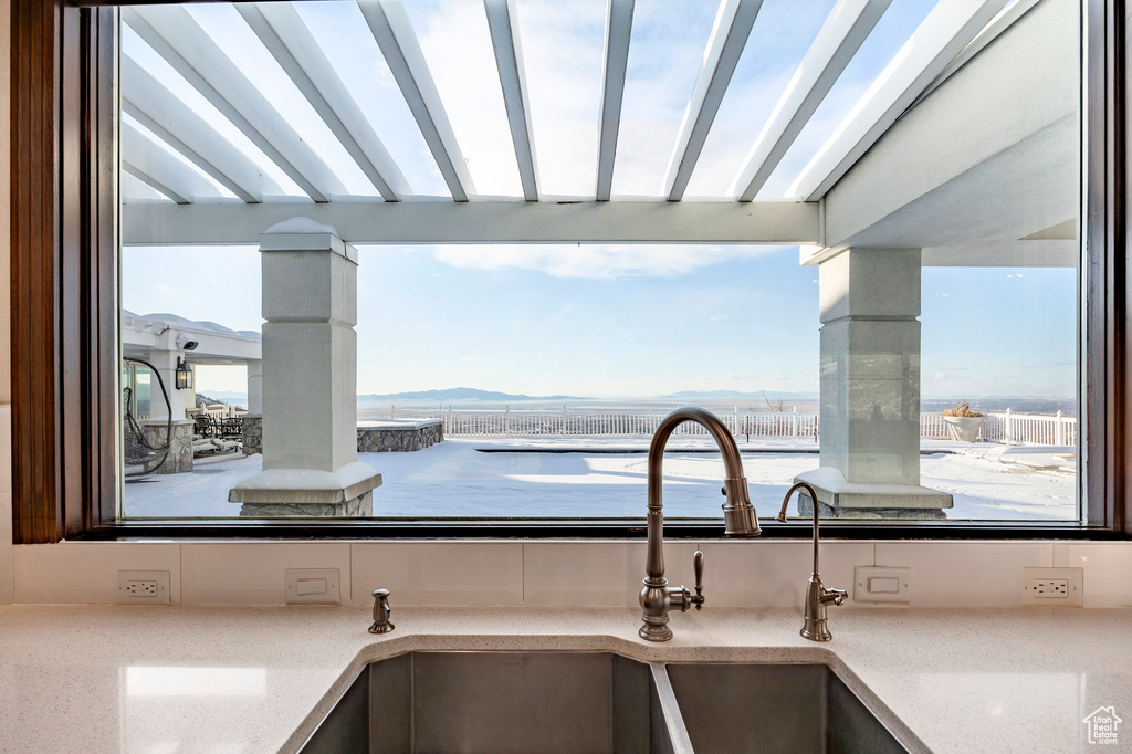 Kitchen view of a mountain view, light stone counters, and a sink