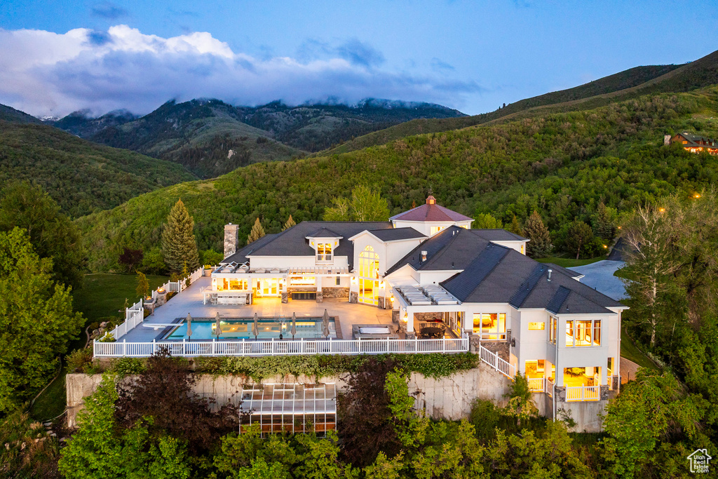 Aerial view of property and surrounding area with a heavily wooded area and a mountain backdrop
