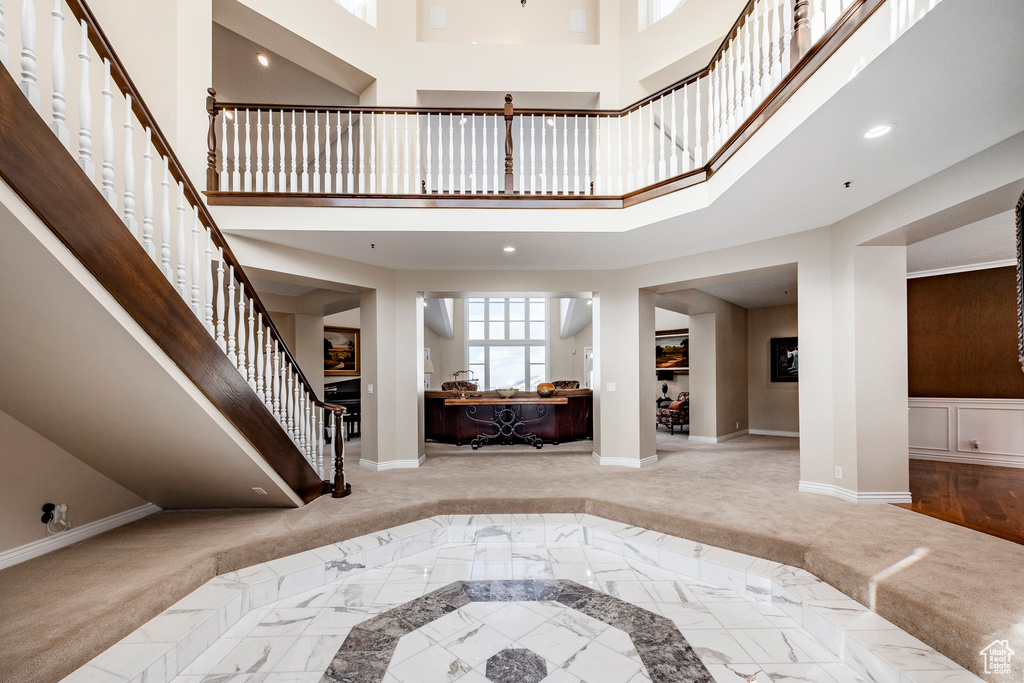 Entrance foyer with baseboards, inlaid floor details, stairs, a towering ceiling, and marble finish flooring