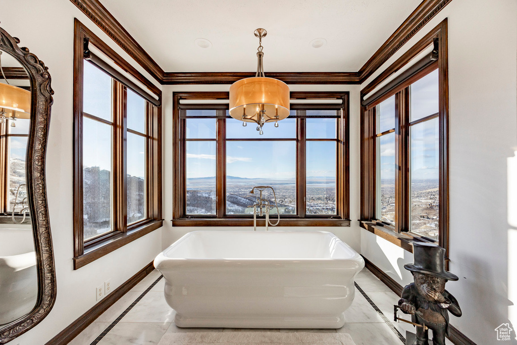 Bathroom featuring a chandelier, inlaid floor details, baseboards, a freestanding bath, and crown molding