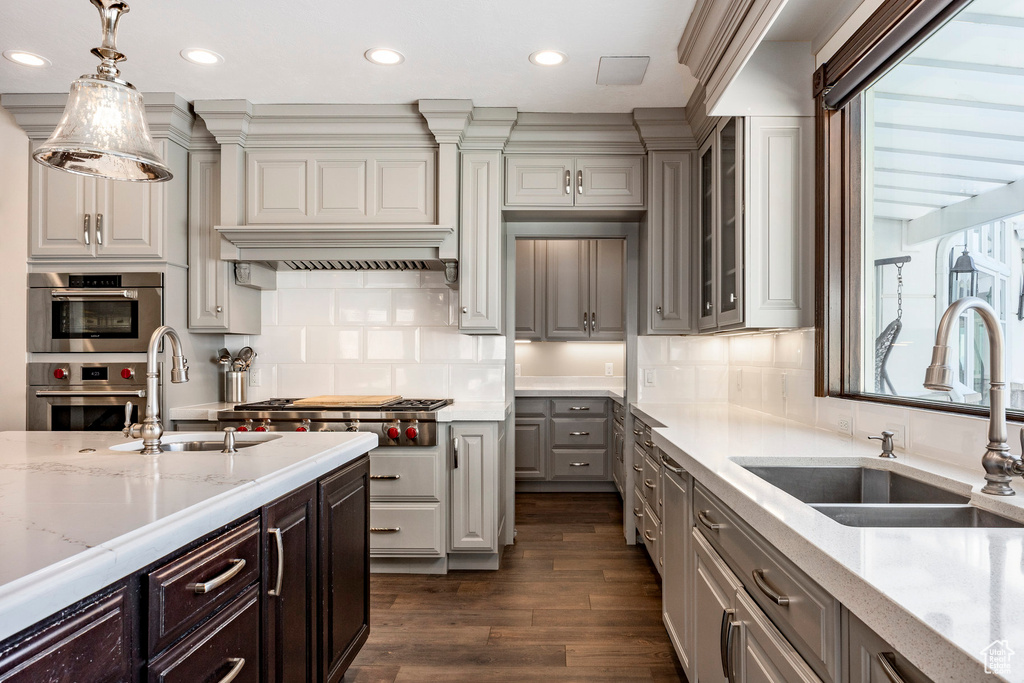 Kitchen with a sink, appliances with stainless steel finishes, recessed lighting, dark wood-style floors, and light stone counters