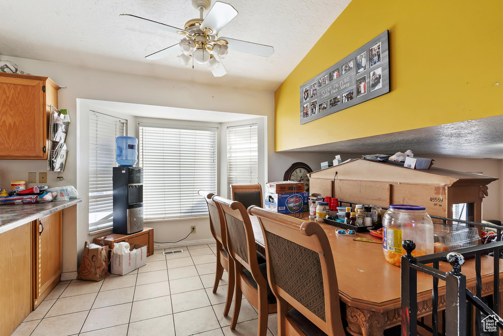 Dining space featuring light tile patterned floors, ceiling fan, and a textured ceiling