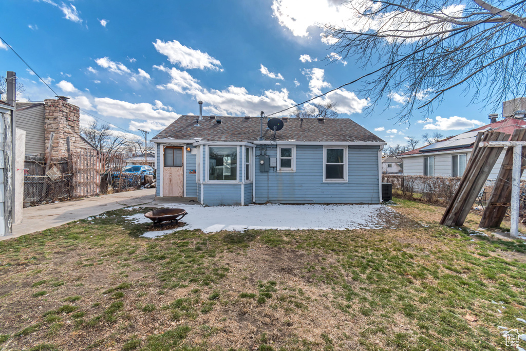 Rear view of property with an outdoor fire pit and a lawn