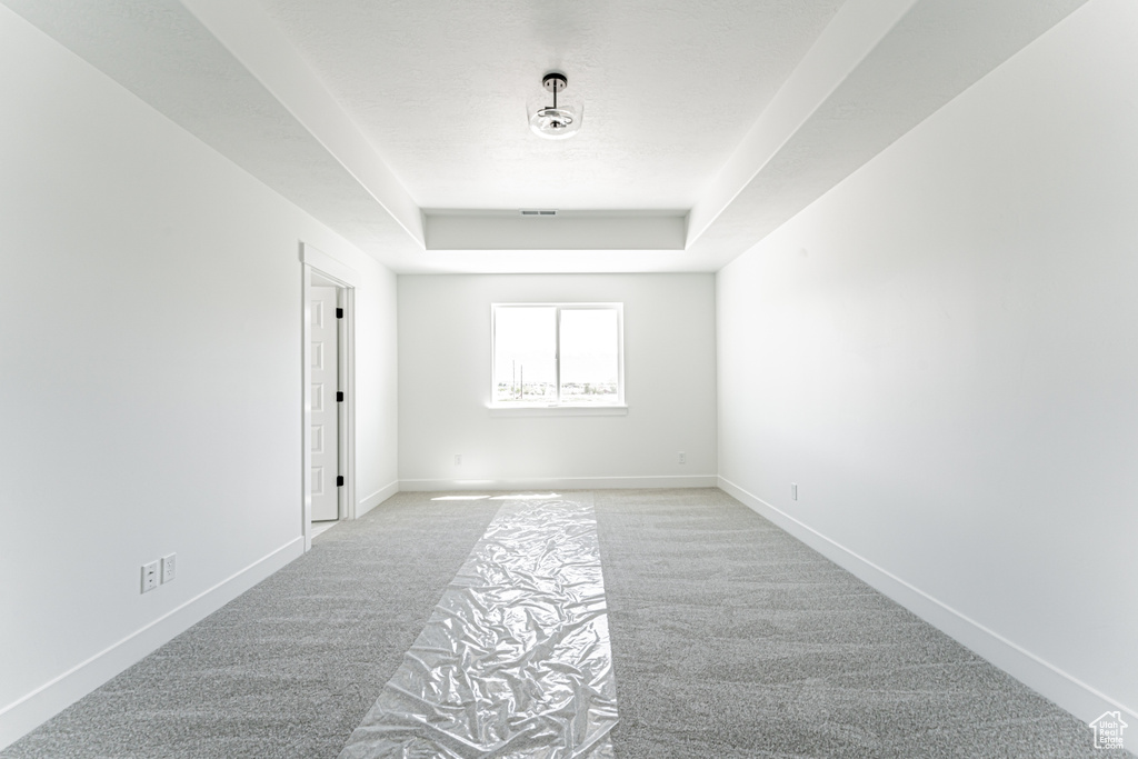 Unfurnished room with carpet flooring, a tray ceiling, and baseboards