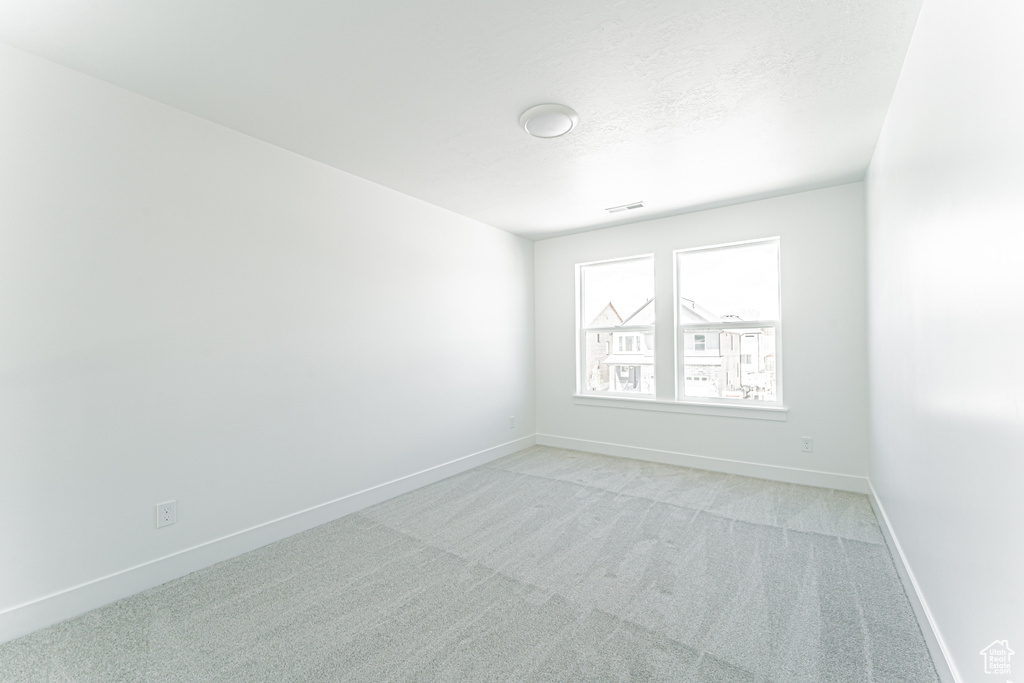 Empty room featuring light colored carpet and baseboards