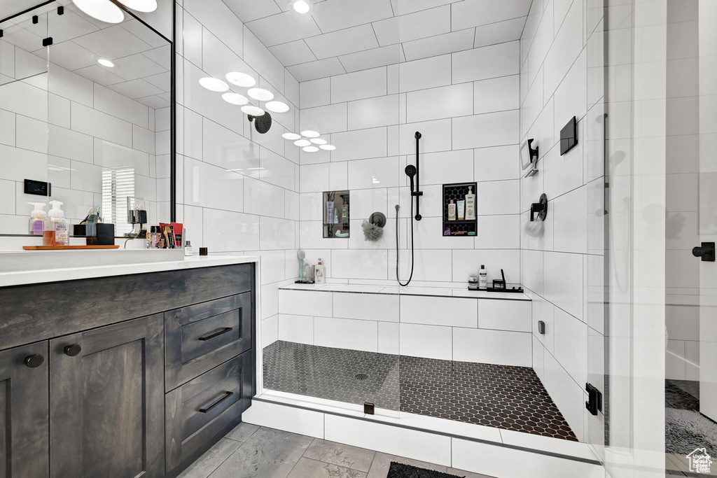 Bathroom featuring a stall shower, vanity, and tile walls