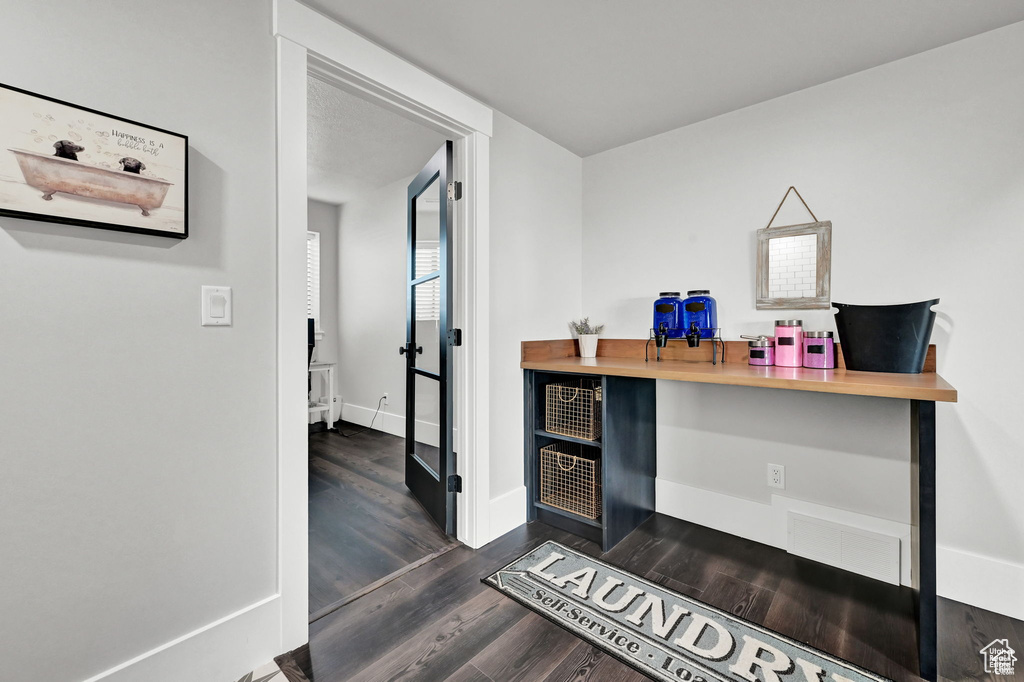 Office with dark wood finished floors, visible vents, and baseboards