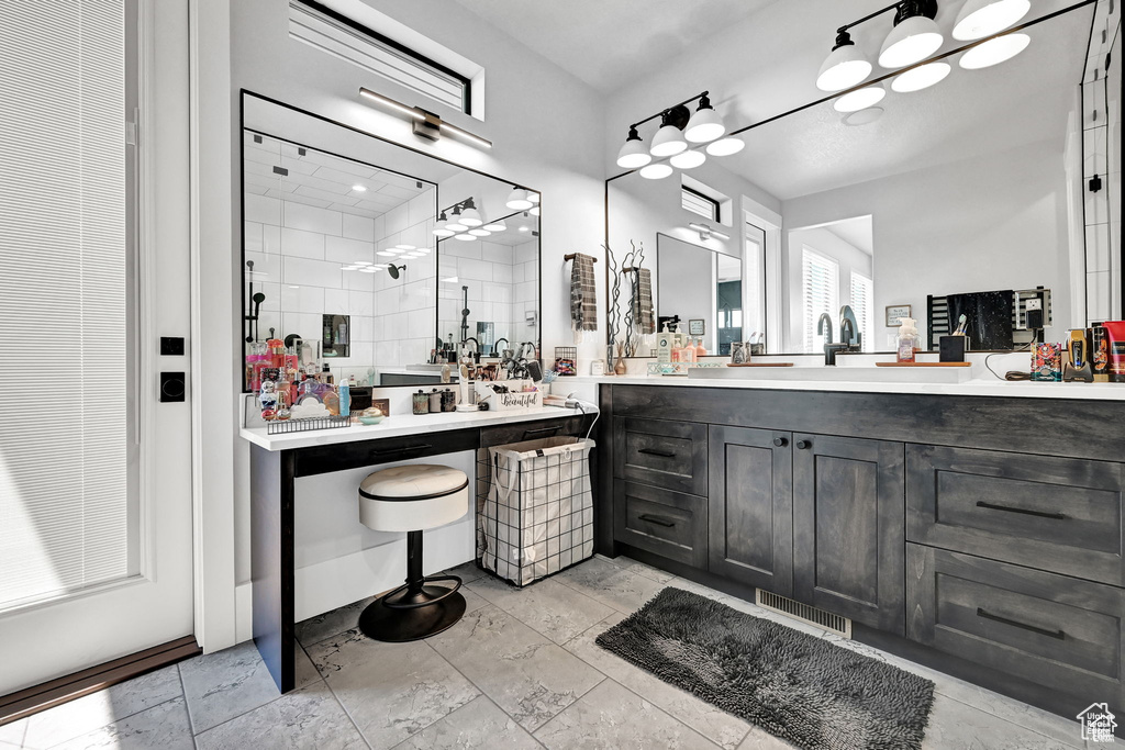 Bathroom with visible vents, vanity, and a tile shower