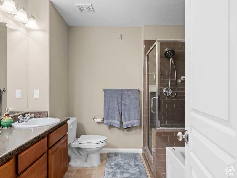 Bathroom featuring toilet, vanity, tile patterned flooring, and a shower with door