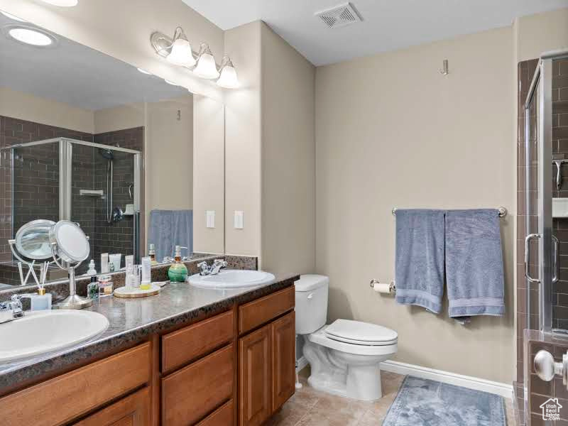 Bathroom featuring tile patterned floors, toilet, vanity, and walk in shower