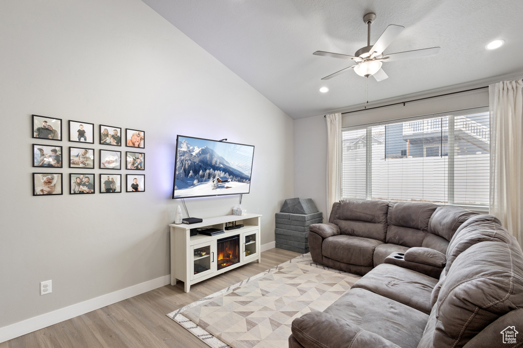 Living room with light hardwood / wood-style floors, vaulted ceiling, and ceiling fan