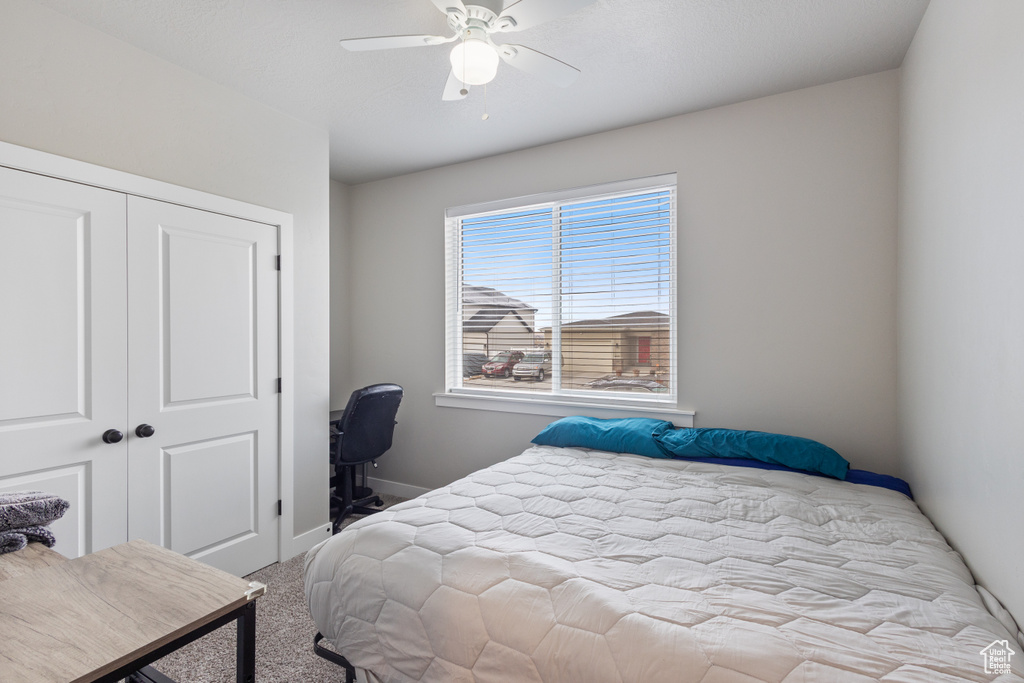 Bedroom with ceiling fan, a closet, and light colored carpet