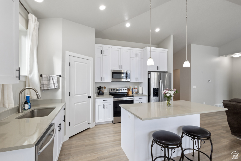 Kitchen with white cabinets, a center island, stainless steel appliances, and sink