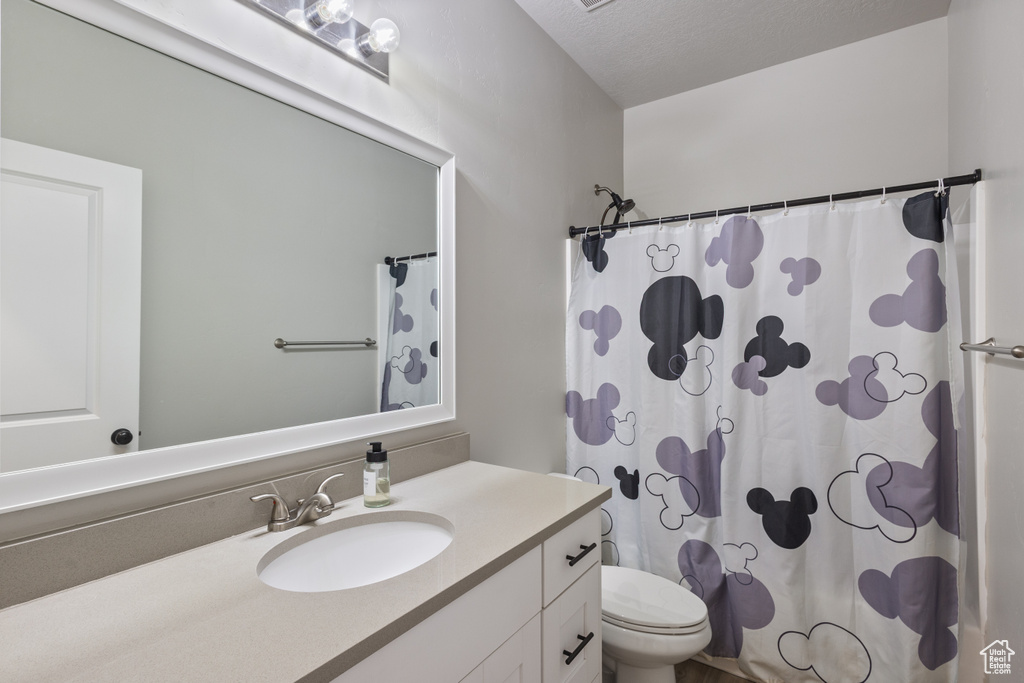Bathroom with a shower with shower curtain, vanity, and toilet