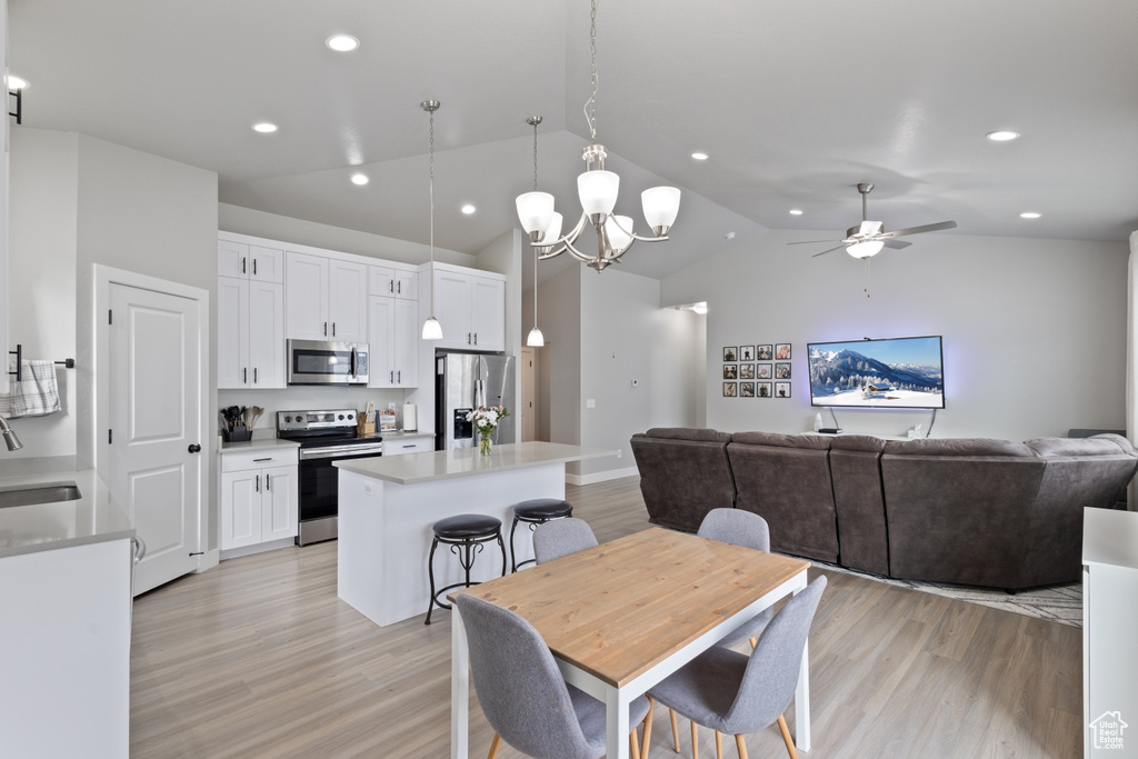 Dining space featuring ceiling fan, sink, vaulted ceiling, and light wood-type flooring