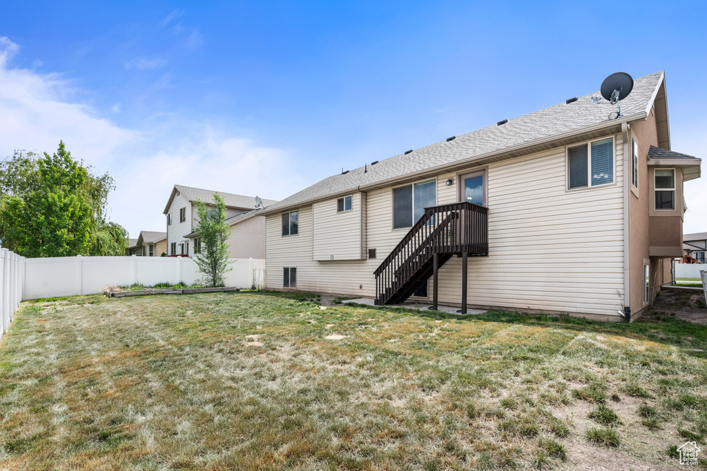 Back of property with a lawn, a fenced backyard, and stairs