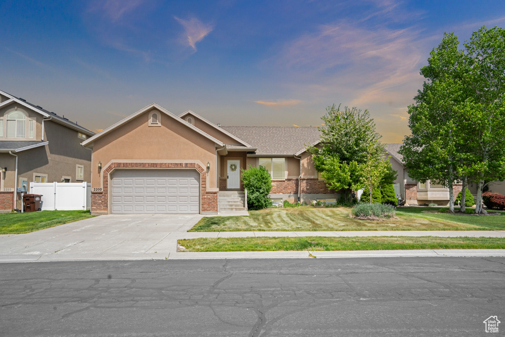 View of front facade featuring fence, brick siding, driveway, a garage, and a front yard