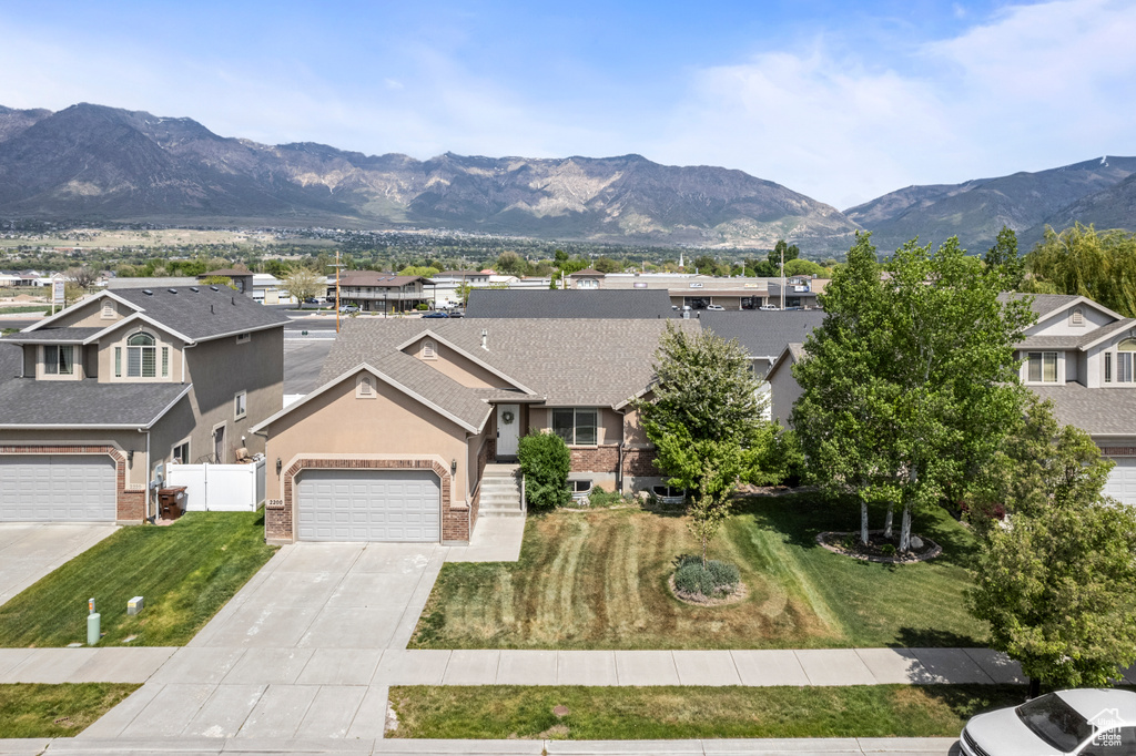 View of front of property featuring driveway, a mountain view, a garage, stucco siding, and a residential view