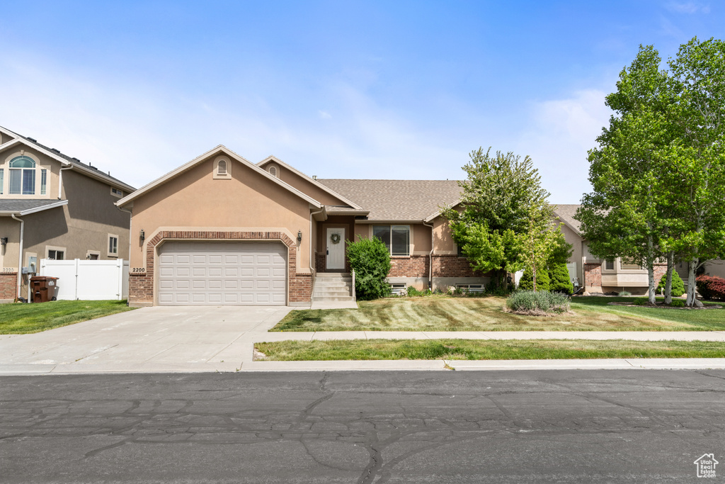 Ranch-style home featuring fence, brick siding, concrete driveway, a garage, and stucco siding