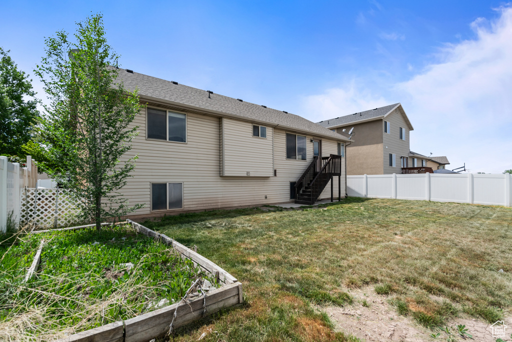 Rear view of property with a vegetable garden, stairway, a lawn, and a fenced backyard