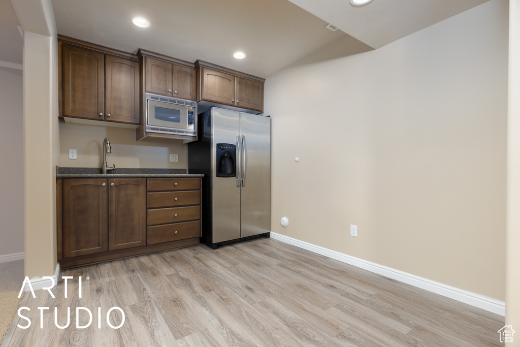 Kitchen featuring light wood-type flooring, sink, appliances with stainless steel finishes, and dark brown cabinets