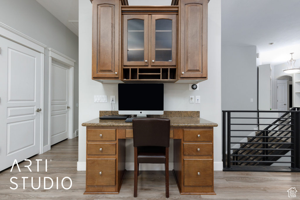 Office area with light hardwood / wood-style floors and built in desk