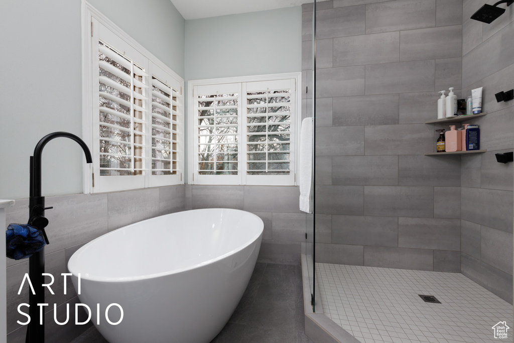 Bathroom featuring tile walls and shower with separate bathtub