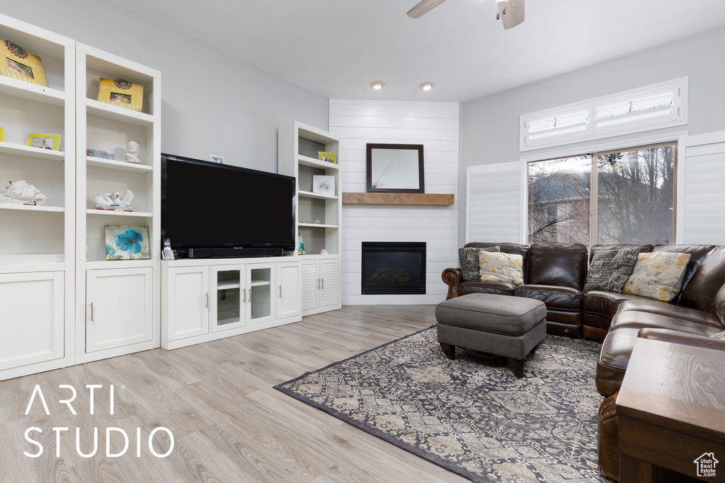 Living room featuring ceiling fan, a fireplace, light hardwood / wood-style floors, and built in features