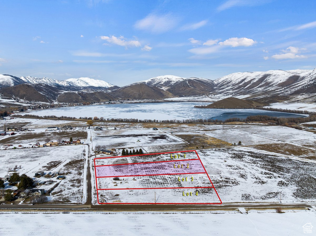 Snowy aerial view featuring property parcel outlined and a mountain view