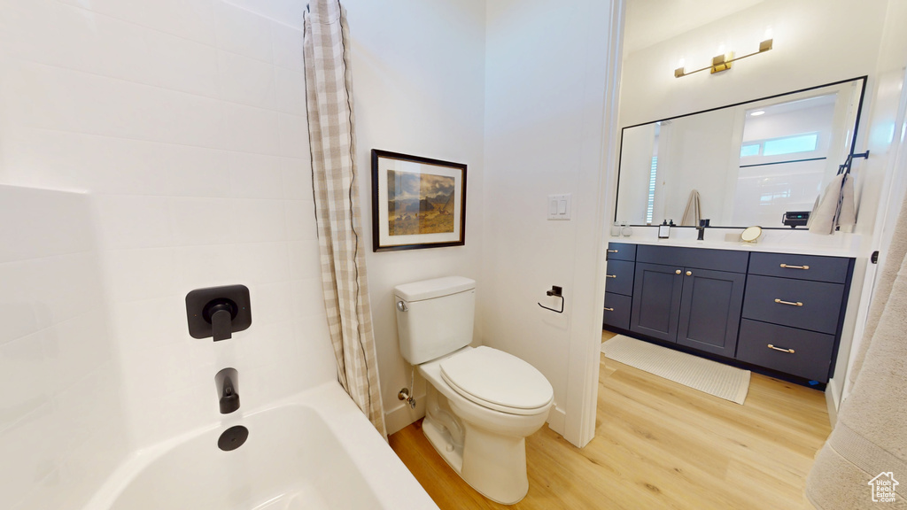 Full bathroom featuring bathtub / shower combination, toilet, wood finished floors, and vanity