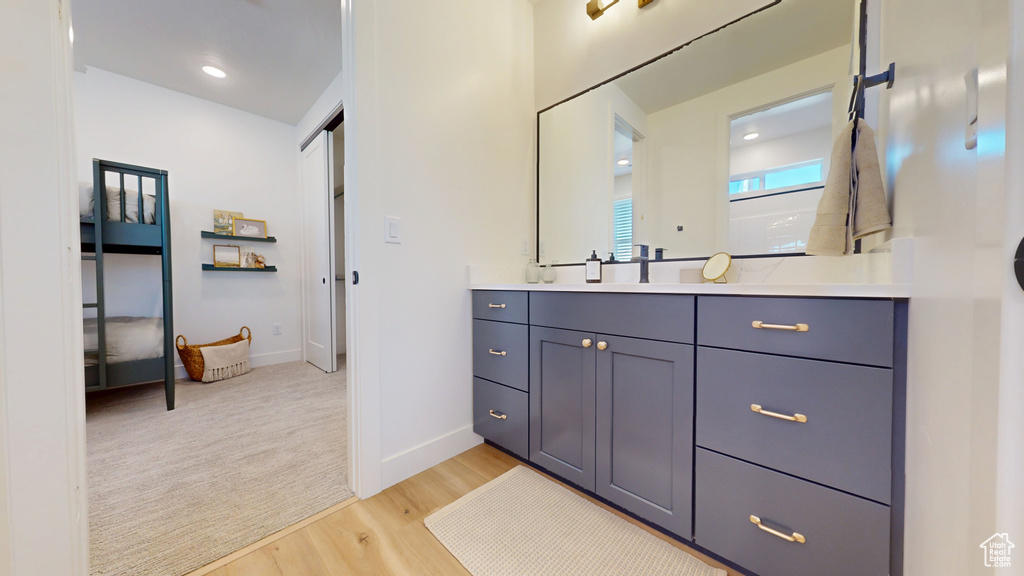 Bathroom featuring recessed lighting, vanity, baseboards, and wood finished floors