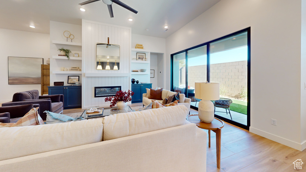 Living room featuring a ceiling fan, recessed lighting, a large fireplace, light wood-style floors, and baseboards