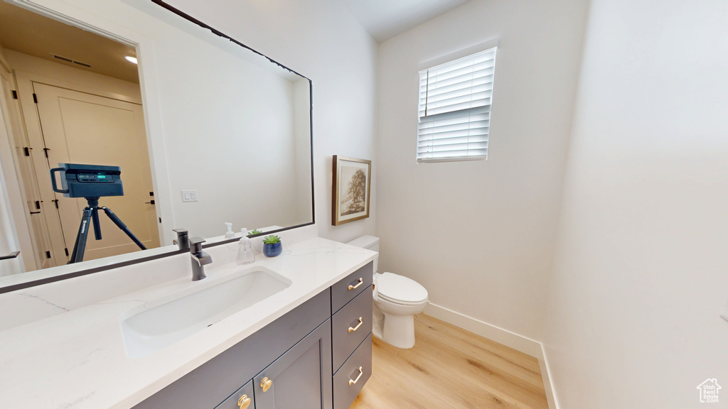 Bathroom featuring visible vents, toilet, wood finished floors, baseboards, and vanity