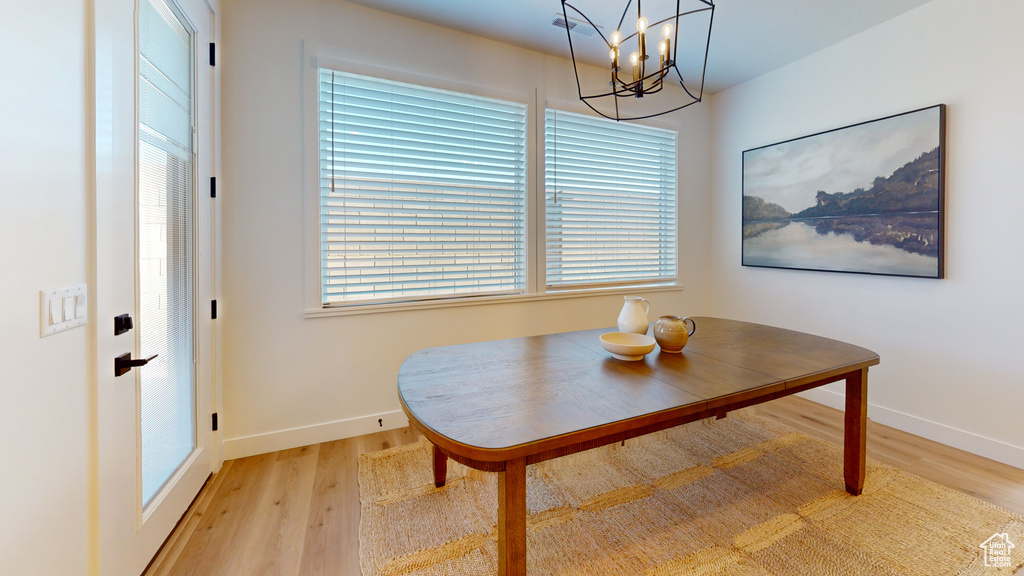 Dining area featuring baseboards, a notable chandelier, and light wood finished floors
